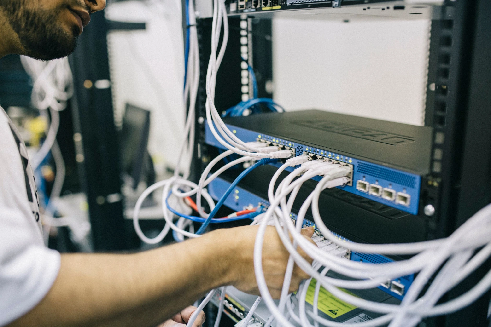 Technicus sluit netwerkkabels aan in een serverrack bij een kmo
